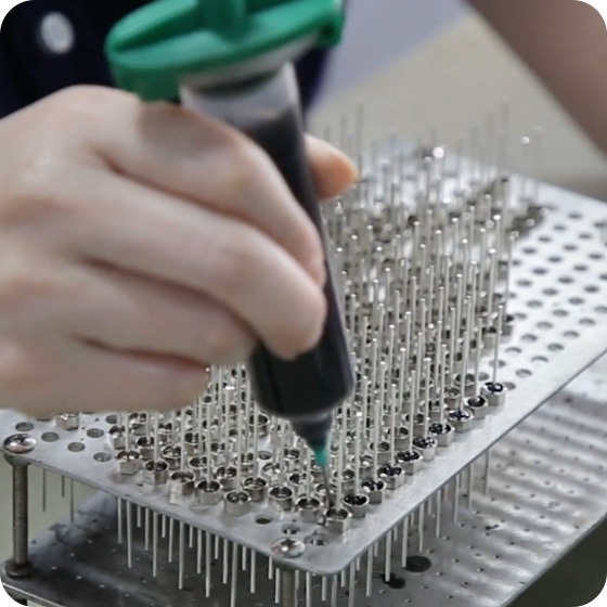 Technician performing precision assembly of EMI filter electronic components on a manufacturing fixture