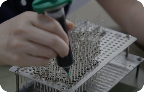 Technician manually assembling precision EMI filter and EMC electronic components in a manufacturing process